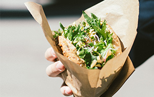 Hand holding a vegan burger with salad